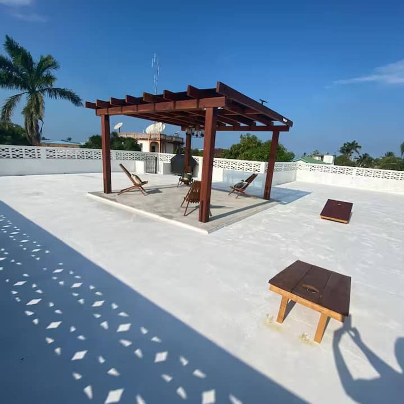 White rooftop deck with pergola under blue sky